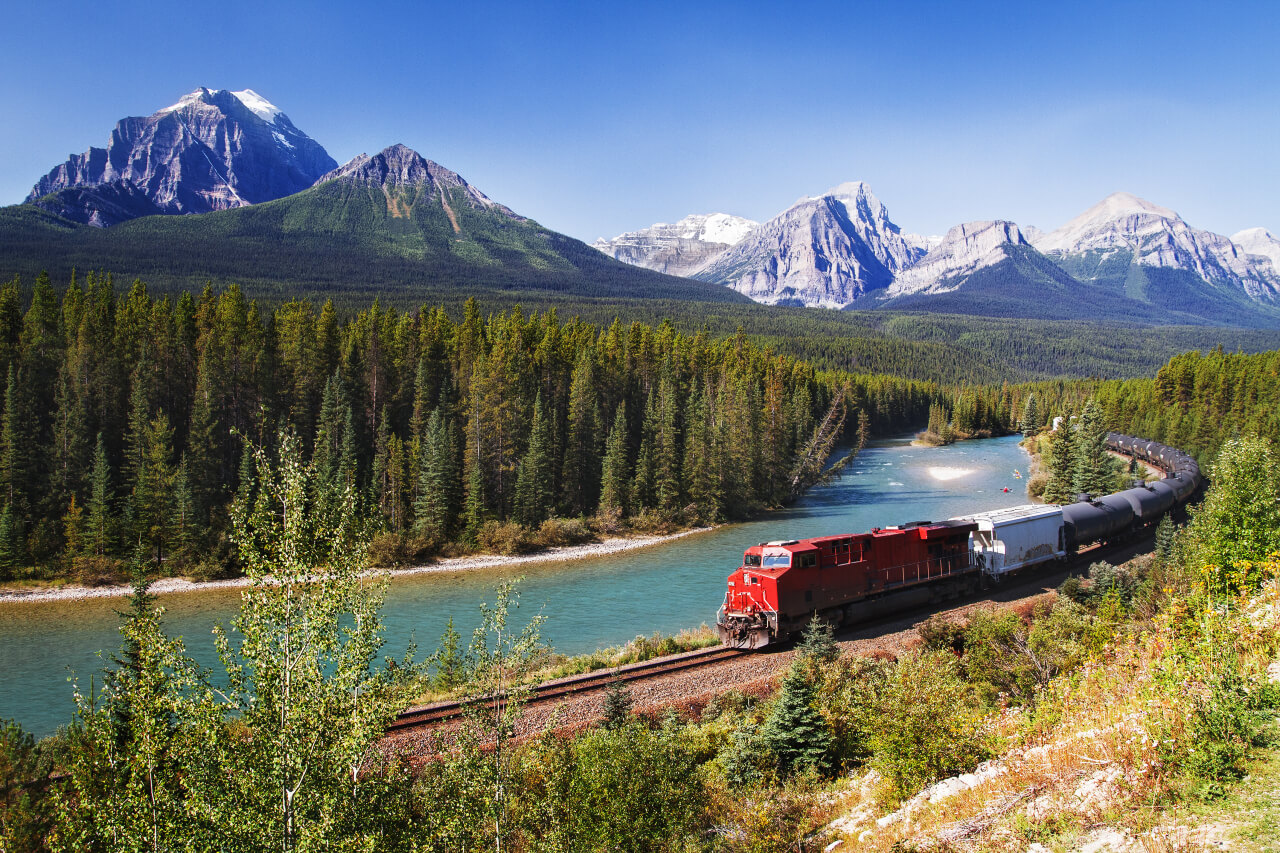Train passing through Bow Valley, Alberta under the surveillance of mighty Rocky Mountains