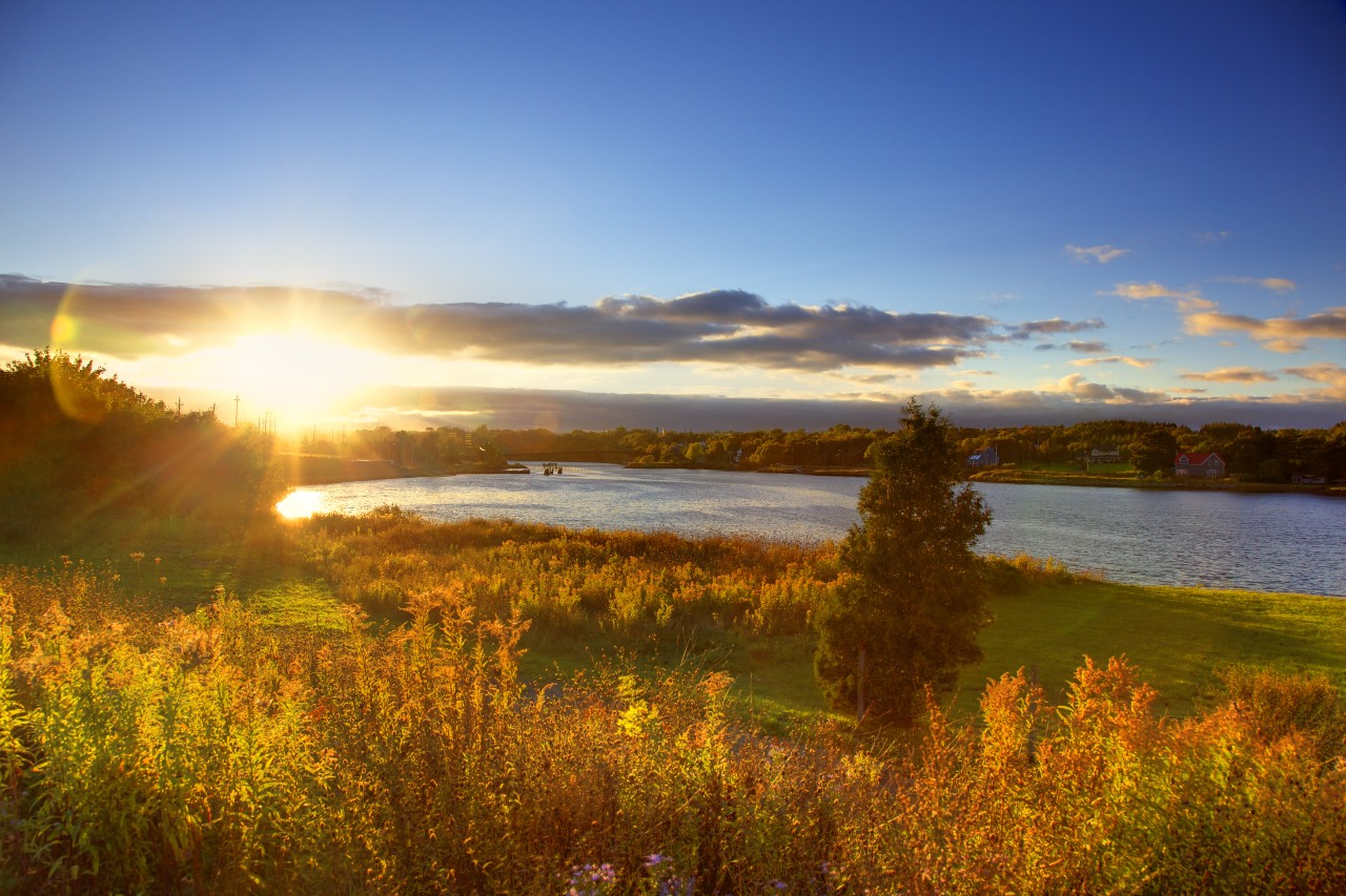 The sun sets on Nova Scotia Gaming Coporation. A beautiful sunset over river with autumn trees in foreground in Sydney, NS