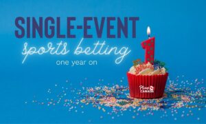 Single-event sports betting in Canada one year on. Image. Red cupcake with a single red 1 candle on blue background with colourful candy sprinkles all around