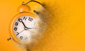 Dissolving orangey-yellow alarm clock on orangey-yellow background